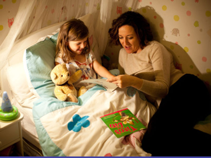 woman reading to a young girl in bed