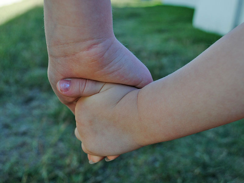 adult hand holding a child's hand