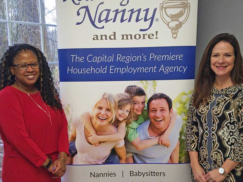 the staff of A New England Nanny standing by the company sign