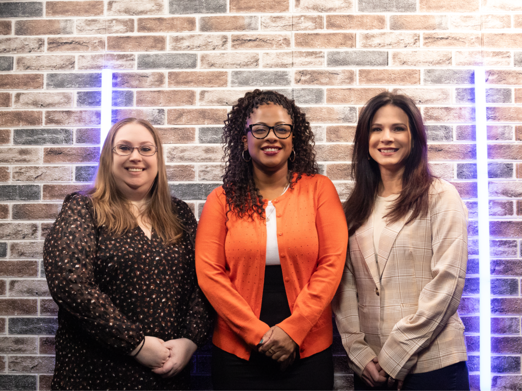 the staff of A New England Nanny standing by the company sign